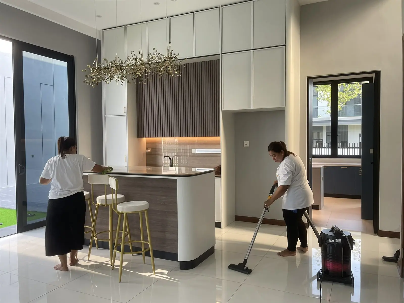 Antz cleaning team wiping a kitchen island and vacuuming the floor